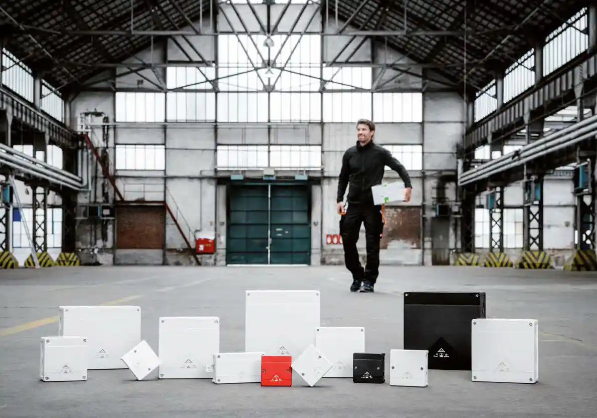 A Spelsberg engineer walking through a warehouse past a range of enclosures, from small junction boxes to distribution boards